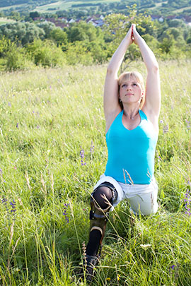 Die Yoga-Lehrerin macht dieselbe Stellung wie im oberen Bild, aber diesmal auf einer Frühlingswiese.